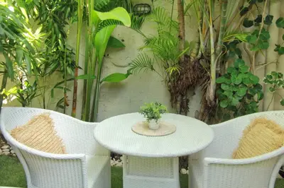 a table and chairs with a white table and a plant at Frangipani Villa Seminyak - 2BR Pool Walk to Beach in Seminyak
