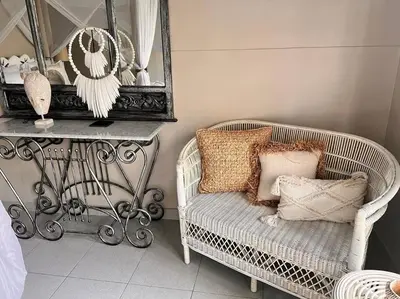 a room with a wicker chair with pillows and a mirror at Frangipani Villa Seminyak - 2BR Pool Walk to Beach in Seminyak