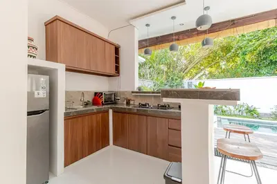 a kitchen with wooden cabinets and a large window at Villa Aliran - Modern Comfort in tranquil Umalas in Canggu