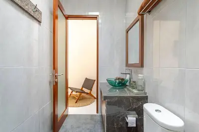 a bathroom with a sink and a toilet and a mirror at Villa Aliran - Modern Comfort in tranquil Umalas in Canggu