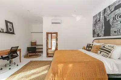 a bedroom with a bed and a desk and a mirror at Villa Aliran - Modern Comfort in tranquil Umalas in Canggu