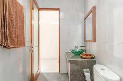 a bathroom with a white toilet and a sink at Villa Aliran - Modern Comfort in tranquil Umalas in Canggu
