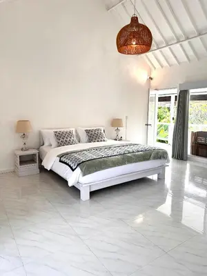 a white bedroom with a large bed in it at Greenhouse Villa in Kerobokan