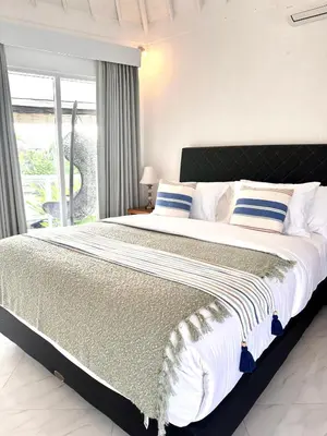 a bedroom with a large bed with blue and white pillows at Greenhouse Villa in Kerobokan