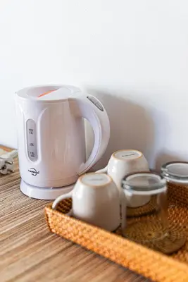 a toaster and three cups on a wooden table at Tirta Mumbul Villa in Badung