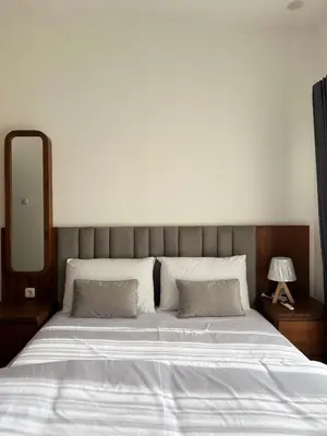 a bedroom with a large white bed with a mirror at Louise villa in Jimbaran
