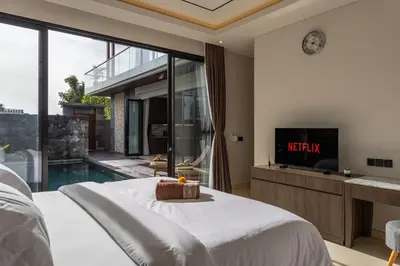 a bedroom with a bed and a tv and a pool at Luxury Chic 3bd Modern Villa in Umalas in Kerobokan