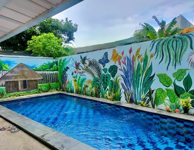 a wall with a mural of a swimming pool at Carstenzs Home Kuta in Kuta