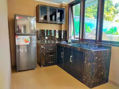 a kitchen with a stainless steel refrigerator and a window at Carstenzs Home Kuta in Kuta
