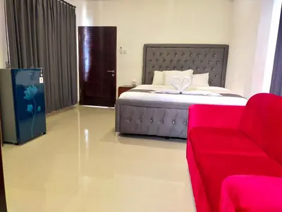a bedroom with a bed and a red couch at Carstenzs Home Kuta in Kuta