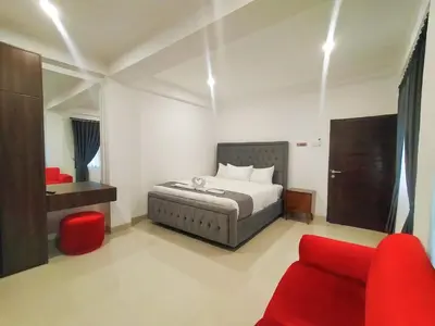 a bedroom with a bed and a red chair at Carstenzs Home Kuta in Kuta