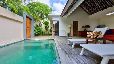 a pool in a house with a dog sitting on a chair at The Decks Bali in Legian