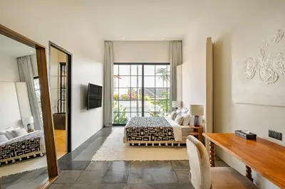 a bedroom with a bed and a desk and a window at Casa Siella in Canggu