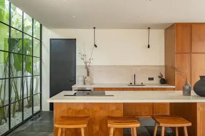 a kitchen with wooden cabinets and a counter with stools at Casa Siella in Canggu