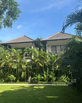a house with palm trees in front of it at Amazing Garden Room with Private Pool at Anwa Bali in Canggu