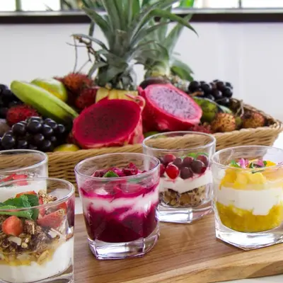 a table with four glasses of desserts and a basket of fruit at Amazing Garden Room with Private Pool at Anwa Bali in Canggu