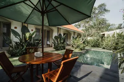 a table and chairs with an umbrella on a patio at D'Leafy Seminyak in Seminyak