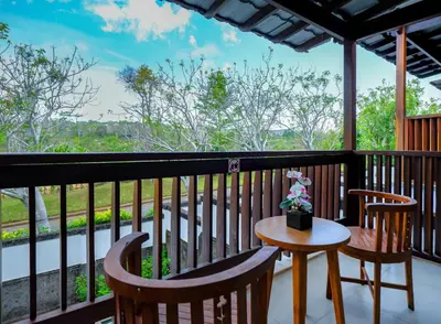 a balcony with two chairs and a table with flowers on it at The Springs Villas Jimbaran in Jimbaran