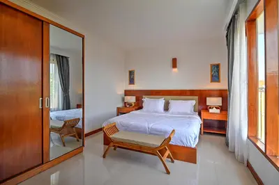 a bedroom with a bed and a chair and a mirror at PRIVATE 3BR - Yash Villa at Seminyak in Kerobokan