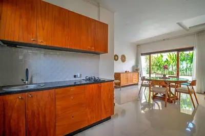 a kitchen with wooden cabinets and a table with chairs at PRIVATE 3BR - Yash Villa at Seminyak in Kerobokan