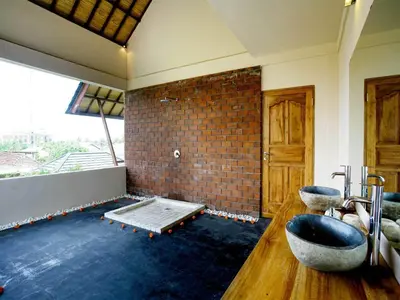 a room with a brick wall and a bath tub at Villa Cokelat in Canggu