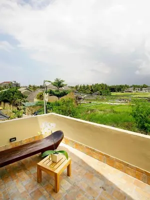 a balcony with a bench and a view of a field at Villa Cokelat in Canggu