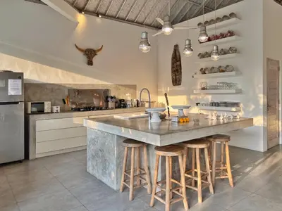 a kitchen with a large island with bar stools at Villa Rocher - Modern 3 BR Villa Batu Belig 3 min beach in Seminyak