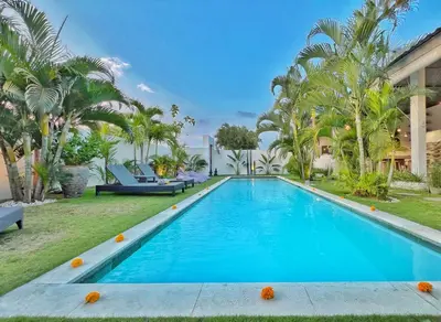 a swimming pool in the backyard of a house with palm trees at Villa Rocher - Modern 3 BR Villa Batu Belig 3 min beach in Seminyak