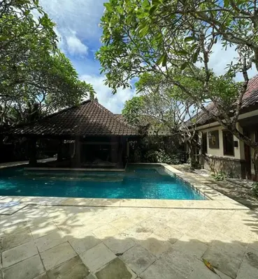 a swimming pool in front of a house at Villa Gadja Bali in Jimbaran
