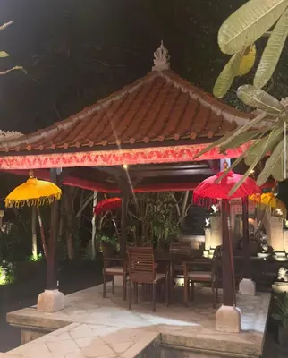 a pavilion with chairs and red and yellow umbrellas at Villa Gadja Bali in Jimbaran