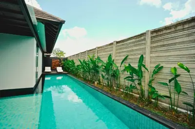 a swimming pool in front of a building with a fence at Jivala 1 BR Private Pool Villa in Seminyak