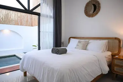 a bedroom with a white bed and a window at Eunoia Villa in Jimbaran