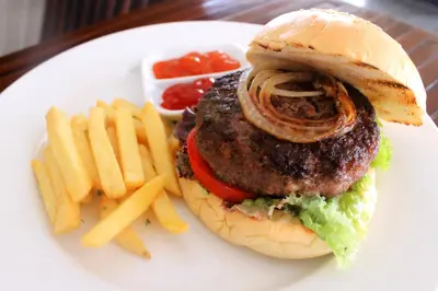 a white plate with a hamburger and french fries at Rofa Kuta Hotel - CHSE Certified in Legian