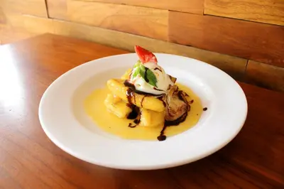 a white plate of food on a wooden table at Rofa Kuta Hotel - CHSE Certified in Legian