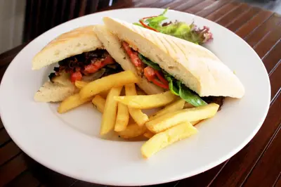 a sandwich and french fries on a white plate at Rofa Kuta Hotel - CHSE Certified in Legian