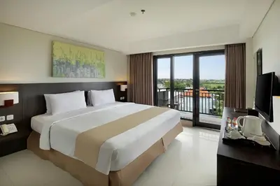 a bedroom with a large bed and a balcony at Rofa Kuta Hotel - CHSE Certified in Legian