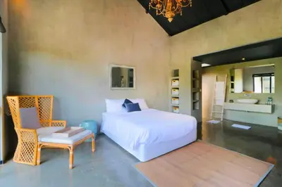 a bedroom with a bed and a chair and a bathroom at Saanvi 2 BR Private Pool Villa in Canggu