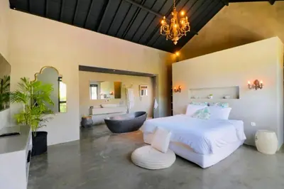 a bedroom with a large white bed and a black chair at Bintarti 3 BR Private Pool Villa in Canggu