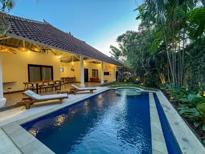 a swimming pool in front of a house at Uma dharma villas in Seminyak