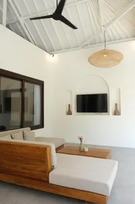 a bedroom with a bed and a tv on the wall at Uma dharma villas in Seminyak