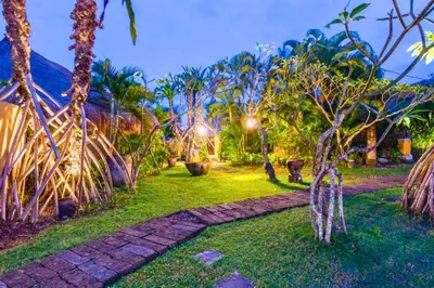 a garden with palm trees and a pathway at Vanshika 1 BR Garden Villa Shared Pool in Sanur