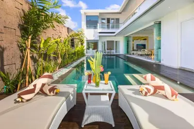 a swimming pool with two chaise lounges next to a house at Nayana 4 BR Private Pool Villa in Legian