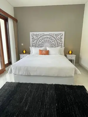 a bedroom with a large white bed with two lamps at CASA NOOA Kerobokan in Kerobokan