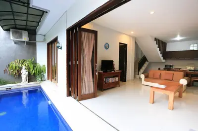 a living room with a swimming pool next to a house at Nyoman Villa Sanur in Sanur