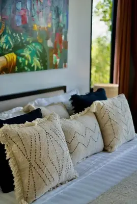 a group of pillows on a bed with a painting at Villa J in Nusa Dua
