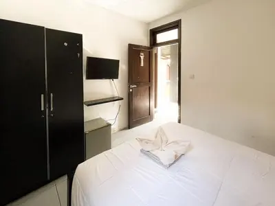 a bedroom with a white bed with a bow on it at arimanu rooms in Kuta