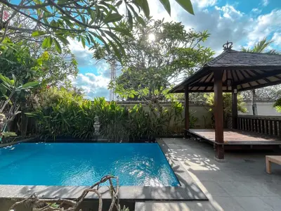 a swimming pool with a gazebo next to a house at arimanu rooms in Kuta