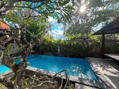 a swimming pool in the middle of a garden at arimanu rooms in Kuta