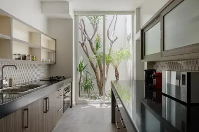 a kitchen with a large window with a view of trees at Villa Levi by GORO in Seminyak