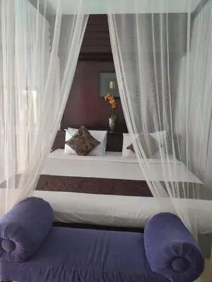 a bedroom with a bed with white curtains and purple pillows at Private villa with swimming pool in Kuta